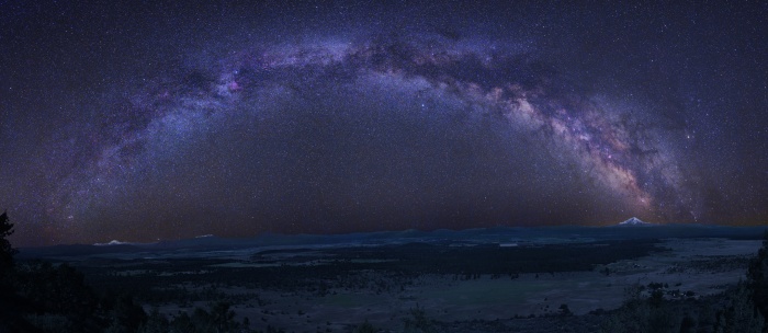 
	A Graceful Arc: Milky Way
	Astronomy Picture of the Day - 2009 December 25
	Credit & Copyright: Tony Hallas
	
	Explanation: The graceful arc of the Milky Way begins and ends at two mountain peaks in this solemn night sky panorama. Created from a 24 frame mosaic, exposures tracking Earth and sky were made separately, with northern California's Mount Lassen at the left and Mount Shasta at the far right, just below the star and dust clouds of the galactic center. Lassen and Shasta are volcanoes in the Cascade Mountain Range of North America, an arc of the volcanic Pacific Ring of Fire. In the dim, snow-capped peaks, planet Earth seems to echo the subtle glow of the Milky Way's own faint, unresolved starlight.