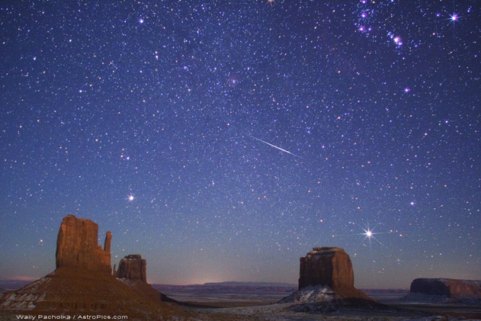 
	Geminid Meteor over Monument Valley
	Astronomy Picture of the Day - 2009 December 12
	Credit & Copyright: Wally Pacholka (AstroPics.com, TWAN)
	
	Explanation: The Geminids are expected to put on a good show this year. Created as planet Earth sweeps through dusty debris from extinct comet Phaethon, the annual Geminid meteor shower is predicted to peak on December 14th, around 0510 UT (12:10am EST). With better viewing for northern hemisphere observers, pictures of Geminids streaking through the night could include wintery landscapes, like this snow-tinged image of a 2007 Geminid meteor over buttes of the Monument Valley region in the southwestern US. The meteor streak points back to the constellation Gemini and the shower's radiant point, just off the upper left edge of the scene. Along with Rigel, the sword and belt stars of Orion are at the upper right. Near the eastern horizon are bright stars Procyon (left) and Sirius. The two buttes at the far left are known as The Mittens - clearly a reminder that if you want to watch a meteor shower on a cold December night, wearing mittens would be a good idea.