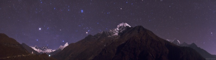 
	Himalayan Skyscape
	Astronomy Picture of the Day - 2009 December 5
	Credit & Copyright: Babak Tafreshi (TWAN)
	
	Explanation: Capella, alpha star of the constellation Auriga, rises over Mt. Everest in this panoramic view of the top of the world at night. The scene was recorded in late November near Namche Bazar, Nepal, gateway to the Himalayan mountain range. Moonlight illuminates the famous peaks of Everest (8840 meters) and Lhotse (8516 meters) at the far left, and a stupa (a Buddhist religious monument) in the foreground, along the main trail to the Everest Base Camp. The light in the valley is from the Tengboche Monastery, also along the trail at about 4000 meters. From left to right above the moonlit peaks, the stars of Auriga give way to bright giant star Aldebaran eye of the Taurus the Bull, the Pleiades star cluster, alpha Ceti, and finally alpha Phoenicis of the Phoenix. Peaks and stars can be identified by placing your cursor over the image.