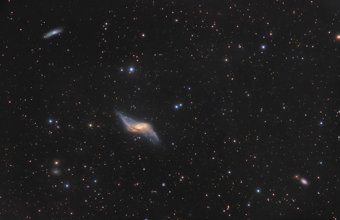
	Polar Ring Galaxy NGC 660
	Astronomy Picture of the Day- 2009 December 3
	Credit & Copyright: Immo Gerber and Dietmar Hager (TAO)
	
	Explanation: NGC 660 lies near the center of this intriguing field of galaxies swimming within the boundaries of the constellation Pisces. Over 20 million light-years away, its peculiar appearance marks it as a polar ring galaxy. A rare galaxy type, polar ring galaxies have a substantial population of stars, gas, and dust orbiting in rings nearly perpendicular to the plane of a flat galactic disk. The bizarre configuration could have been caused by the chance capture of material from a passing galaxy by the disk galaxy, with the captured debris strung out in a rotating ring. Polar Ring galaxies can be used to explore the shape of the galaxy's otherwise unseen dark matter halo by calculating the dark matter's gravitational influence on the rotation of the ring and disk. Broader than the disk, NGC 660's ring spans about 40,000 light-years.
