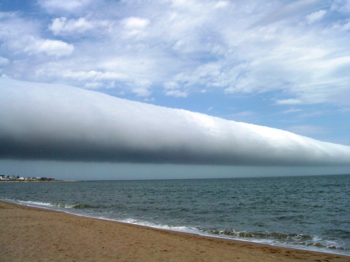 
	A Roll Cloud Over Uruguay
	Credit & Copyright: Daniela Mirner Eberl
	Astronomy Picture of the Day - 2010 January 5
	
	Explanation: What kind of cloud is this? A roll cloud. These rare long clouds may form near advancing cold fronts. In particular, a downdraft from an advancing storm front can cause moist warm air to rise, cool below its dew point, and so form a cloud. When this happens uniformly along an extended front, a roll cloud may form. Roll clouds may actually have air circulating along the long horizontal axis of the cloud. A roll cloud is not thought to be able to morph into a tornado. Unlike a similar shelf cloud, a roll cloud, a type of Arcus cloud, is completely detached from their parent cumulonimbus cloud. Pictured above, a roll cloud extends far into the distance in 2009 January above Las Olas Beach in Maldonado, Uruguay.