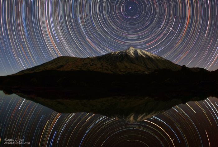 
	Teide Sky Trails
	Credit & Copyright: Daniel López
	Astronomy Picture of the Day - 2010 February 12
	
	Explanation: The snow capped Teide volcano is reflected in a pool of water in this nearly symmetric night sky view from the Canary Island Tenerife. Bright north star Polaris stands above the peak in an exposure that also captures the brilliant trail of a polar orbiting Iridium satellite. Of course, with the camera fixed to a tripod, the stars themselves produce concentric trails in long exposures, a reflection of the Earth's rotation around its axis. In fact, you can add about 4.5 hours of exposure time to this image by just sliding your cursor over the picture. Large astronomical observatories also take advantage of the calm Canary Island sky.