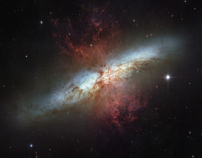    M82: Galaxy with a Supergalactic Wind  Credit: NASA, ESA, The Hubble Heritage Team, (STScI / AURA)  Acknowledgement: M. Mountain (STScI), P. Puxley (NSF), J. Gallagher (U. Wisconsin) Astronomy Picture of the Day - 2010 December 19  Explanation: What's lighting up the Cigar Galaxy? M82, as this irregular galaxy is also known, was stirred up by a recent pass near large spiral galaxy M81. This doesn't fully explain the source of the red-glowing outwardly expanding gas, however. Recent evidence indicates that this gas is being driven out by the combined emerging particle winds of many stars, together creating a galactic superwind.. The above photographic mosaic highlights a specific color of red light strongly emitted by ionized hydrogen gas, showing detailed filaments of this gas. The filaments extend for over 10,000 light years. The 12-million light-year distant Cigar Galaxy is the brightest galaxy in the sky in infrared light, and can be seen in visible light with a small telescope towards the constellation of the Great Bear (Ursa Major).
