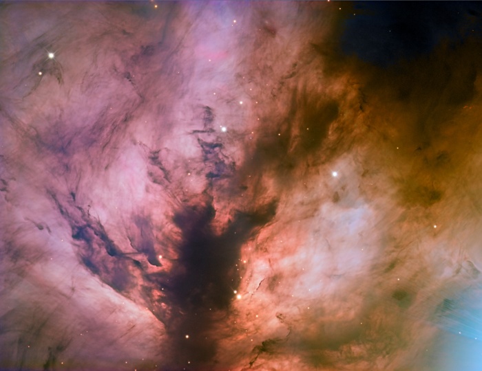 Flame Nebula Close-Up  Credit:   Adam Block, Mt. Lemmon SkyCenter, U. Arizona Astronomy Picture of the Day - 2010 November 26  Explanation: Of course, the Flame Nebula is not on fire. Also known as NGC 2024, the nebula's suggestive reddish color is due to the glow of hydrogen atoms at the edge of the giant Orion molecular cloud complex some 1,500 light-years away. The hydrogen atoms have been ionized, or stripped of their electrons, and glow as the atoms and electrons recombine. But what ionizes the hydrogen atoms? In this close-up view, the central dark lane of absorbing interstellar dust stands out in silhouette against the hydrogen glow and actually hides the true source of the Flame Nebula's energy from optical telescopes. Behind the dark lane lies a cluster of hot, young stars, seen at infrared wavelengths through the obscuring dust. A young, massive star in that cluster is the likely source of energetic ultraviolet radiation that ionizes the hydrogen gas in the Flame Nebula.
