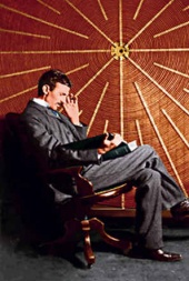 Tesla seated in front of the spiral coil of his high-frequency transformer