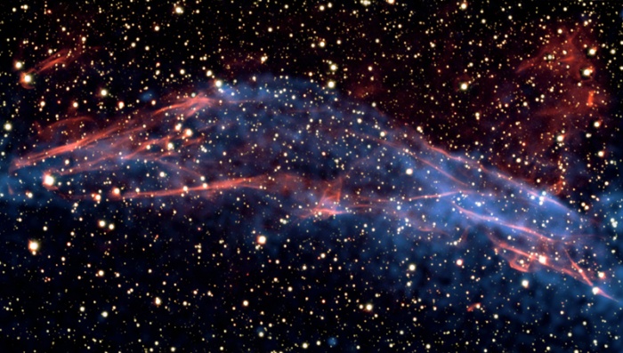 
	This image of data from NASA's Chandra X-ray Observatory and the European Southern Observatory's Very Large Telescope shows a part of the roughly circular supernova remnant known as RCW 86. This remnant is the remains of an exploded star, which may have been observed on Earth in 185 AD by Chinese astronomers. By studying this remnant, a team of astronomers was able to understand new details about the role of supernova remnants as the Milky Way's super-efficient particle accelerators. The team shows that the shock wave visible in this area is very efficient at accelerating particles and the energy used in this process matches the number of cosmic rays observed on Earth.
	
	The VLT data (colored red in the composite) was used to measure the temperature of the gas right behind the shock wave created by the stellar explosion. Using X-ray images from Chandra (blue), taken three years apart, the researchers were also able to determine the speed of the shock wave to be between one and three percent of the speed of light. The temperature found by these latest results is much lower than expected, given the measured shock wave's velocity. The researchers conclude that the missing energy goes into accelerating the cosmic rays.

	Fast Facts for RCW 86:
	Credit Optical: ESO/E. Helder; X-ray: NASA/CXC/Univ. of Utrecht/J.Vink et al.
	Scale Image is about 6 arcmin across
	Category: Supernovas & Supernova Remnants
	Coordinates: (J2000) RA 14h 45m 02.30s | Dec -62º 20' 32.00